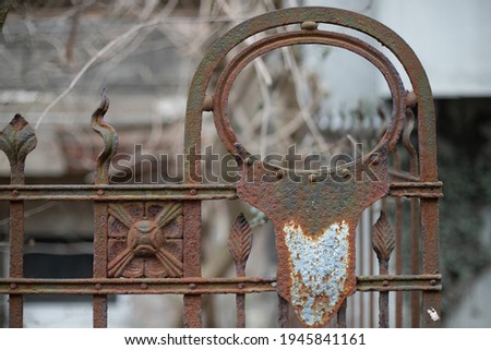 Abandoned places. A fragment of a rusty fence in front of an antiqued building. Vintage metal surface texture. Oval and spikes pattern.