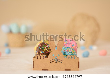 DONUTS! Easter bunny shaped wooden box with colorful sweet donuts inside, and blurred background with colorful easter eggs