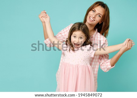 Happy woman in pink clothes have fun with cute child baby girl 5-6 years old. Mommy little kid daughter dancing celebrate isolated on pastel blue background studio. Mother's Day love family concept