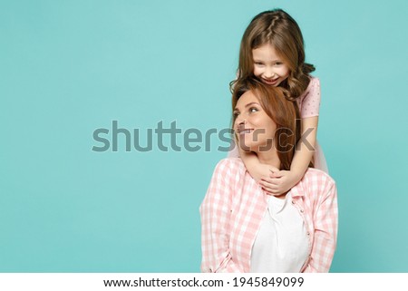 Happy woman in pink clothes have fun with cute child baby girl 5-6 years old Mommy little kid daughter stand behind hug isolated on pastel blue azure background studio Mother's Day love family concept