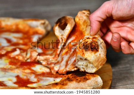 A girl's hand takes a slice of high-dough Neapolitan margherita pizza  based on mozzarella, cheese, buffalo mozzarella, tomato sauce, basil Royalty-Free Stock Photo #1945851280