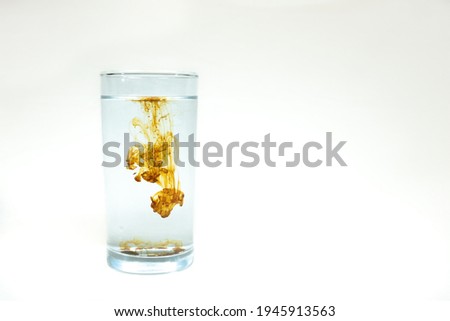 A single drop of concentrated Colloidal Silver being diluted in a glass of water. Room for text.