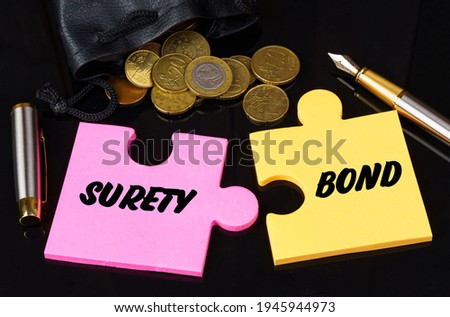 Business and finance concept. Coins are scattered on the black surface, there is a pen and puzzles on which it is written - SURETY BOND Royalty-Free Stock Photo #1945944973
