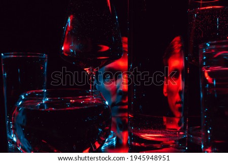 man looking through glass glasses of water with reflections and distortions