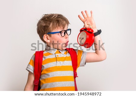 Picture of shocked little boy holding clock alarm. Set up alarm clock. Child hold red clock. It is never too late. Define your own rhythm of life. Happy hours concept. Schedule and timing