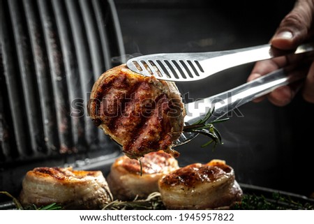 Cooking Fillet Mignon on grill by chef hands. tenderloin meat beef steaks fillet wrapped in bacon. Food recipe background. Close up