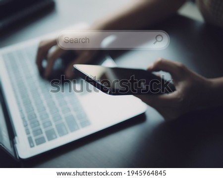 Searching Browsing Internet with smart phone and laptop computer  in office. Search bar of internet browser and man working on modern laptop. Networking Concept. 