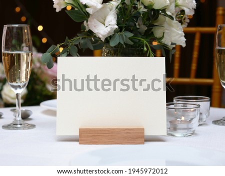 Mockup white blank space card, for greeting, table number, wedding invitation template on wedding table setting background. with clipping path Royalty-Free Stock Photo #1945972012