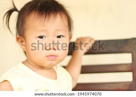 Portrait of Asian little girl sitting chair and looking to camera, Asian baby girl wear ears ring