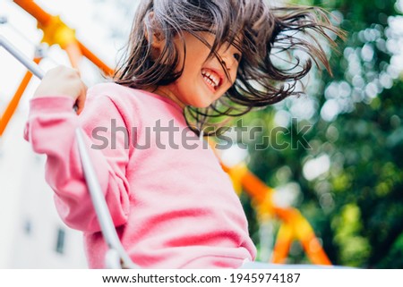 Girl playing with swing at a park Royalty-Free Stock Photo #1945974187