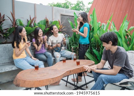asian friends having fun singing and playing guitar together in the backyard