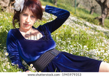 Portrait of beautiful woman in the flowering meadow with blue velvet dress
