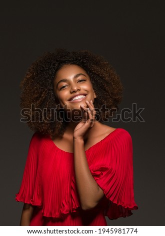 Beautiful african woman girl in red dress over black dark background happy young african model