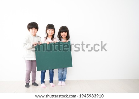 Children holding blackboard together on white background