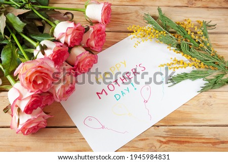 happy mother's day with beautiful bouquet of pink roses an mimosa flowers and card on wooden background, spring flowers flat lay, closeup