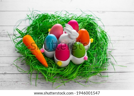 Banner.Easter eggs, carrot and a rabbit basket in a grass nest on a wooden background. The minimal concept of Easter. Top view. An Easter card with a copy of the place for the text.