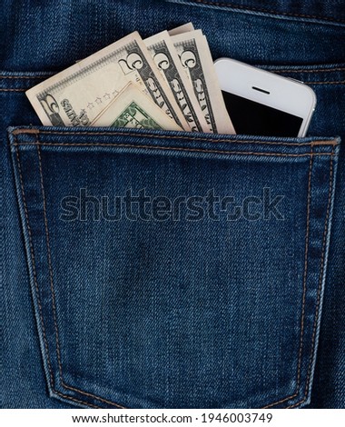 mobile phone and dollar bills in jeans pocket. The concept of expensive telephone calls. Mobile connection. Denim. High quality photo