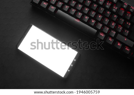 phone and gamer keyboard red lights black background