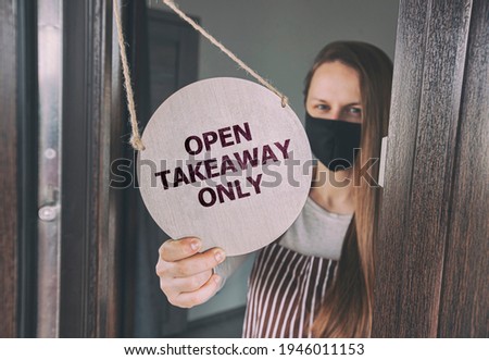 Woman holds the wooden sign with text: Open for take-out 