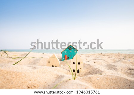 Small house on the beach, building model, wave and sea background, real estate business ideas.