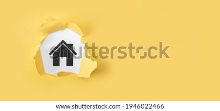 Real estate concept, businessman holding a house icon.House on Hand. Torn yellow paper with house on white background.Property insurance and security concept