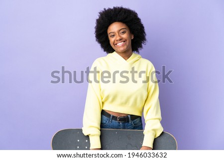 Young African American woman isolated on purple background with a skate with happy expression