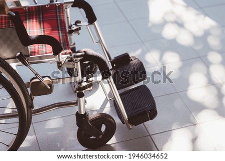 Close up view of empty wheelchair with nature day light on white tile floor, Handicap symbol, Nobody picture, Cinematic tone.