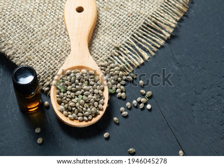 Hemp seeds in a wooden spoon on a black wooden table