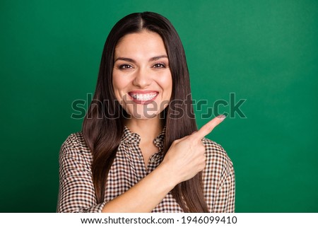 Photo of cheerful pretty lady indicate finger empty space wear checkered shirt isolated green color background