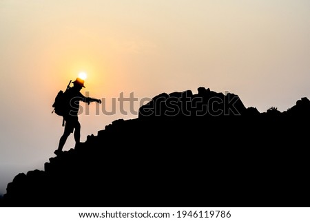 Young male tourists climbing mountains Ideas for personal development and goals in the life of a climber with a backpack. Royalty-Free Stock Photo #1946119786