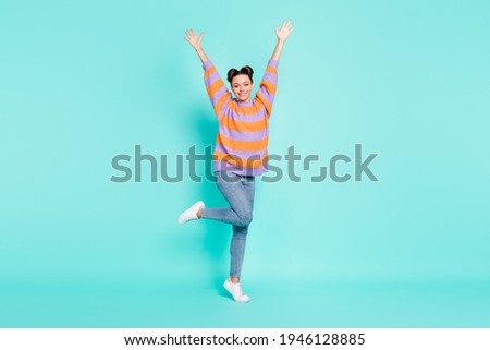Full size portrait of adorable satisfied girl raise arms standing on tiptoe isolated on blue color background