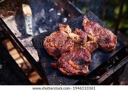 Raw beef burger steak on grill. Cutlet meat placed on grill stone with fire.
