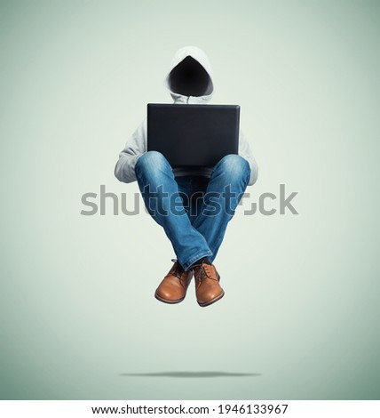 Anonymous hacker in a hooded sweatshirt without a face levitates in the air with a laptop on his lap, on green background. The illusion of power