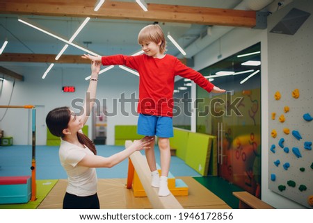 Kids doing balance beam gymnastics exercises in gym at kindergarten or elementary school. Children sport and fitness concept.