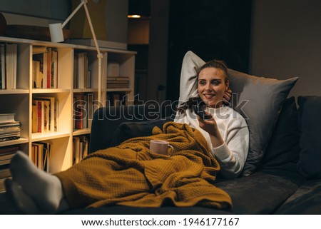 woman relaxing on sofa at her home and watching television