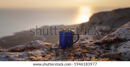 Closeup photo of cup with tea over out of focus mountains view. Trekking concept