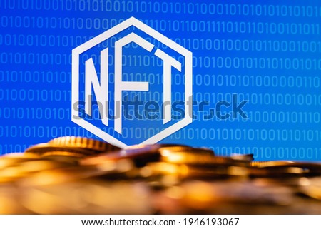 A NFT (non-fungible token) is a special cryptographically-generated token that uses blockchain technology to link with a unique digital asset. NFT symbol with coins in the foreground.
