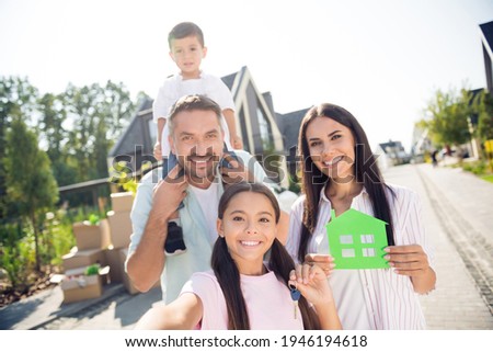 Self-portrait of nice cheerful family small little kids holding in hand home card rent leasing loan credit ownership move-in in cottage outdoor