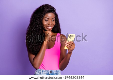 Photo portrait of african american girl holding phone in one hand thinking isolated on pastel pink colored background