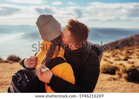 a young couple embracing standing on top of a mountain