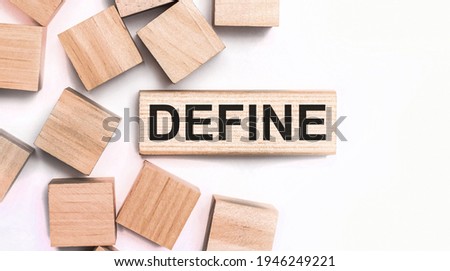 On a light background, wooden cubes and a wooden block with the text DEFINE. View from above
