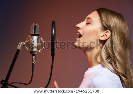 Singer girl with microphone. Closeup profile portrait of young Caucasian girl singing enjoying with closed eyes