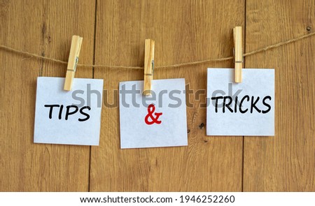 Tips and tricks symbol. White papers on wooden clothespins. Words 'Tips and tricks'. Beautiful wooden background. Business and tips and tricks concept, copy space.