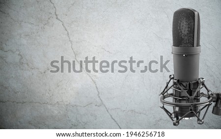 Professional microphone on concrete wall background, urban audio recording