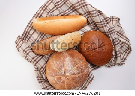 Freshly baked bread loaf bun roll round long mix verity wrapped in checkered kitchen fabric napkin towel over white background