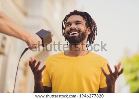 Photo portrait of guy with dreadlocks smiling talking to reporter taking part in public asking speaking in microphone Royalty-Free Stock Photo #1946277820
