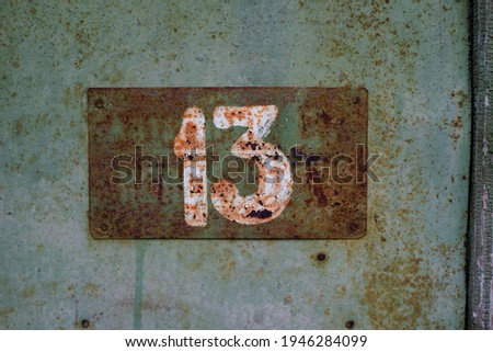 Metal surface with old paint with the number 13                                    