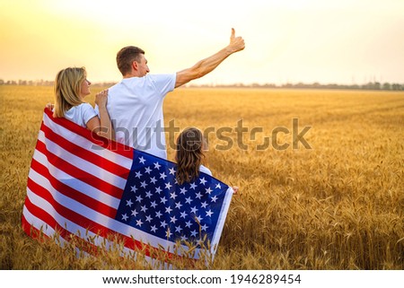 Patriotic holiday. Back view of happy family, parents and daughters children girls with American flag outdoors. USA celebrate 4th of July. High quality photo