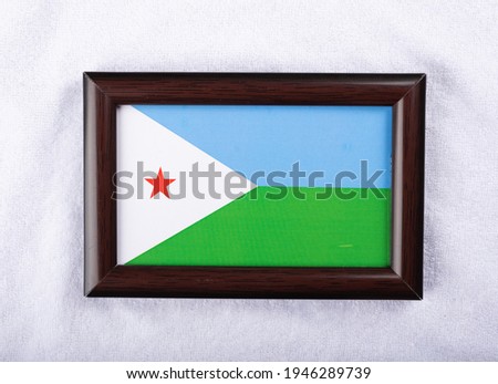 Djibouti flag in a realistic frame on white cloth background flat lay photo