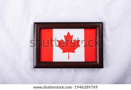 Canada flag in a realistic frame on white cloth background flat lay photo